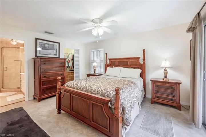 Bedroom with light tile flooring, sliders leading to patio and an en-suite bath