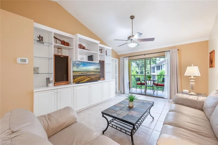 Tiled living room featuring vaulted ceiling, and ornamental molding