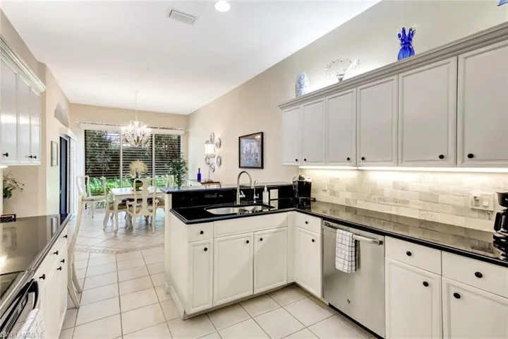 Kitchen with visible vents, a peninsula, a sink, stainless steel dishwasher, and a notable chandelier