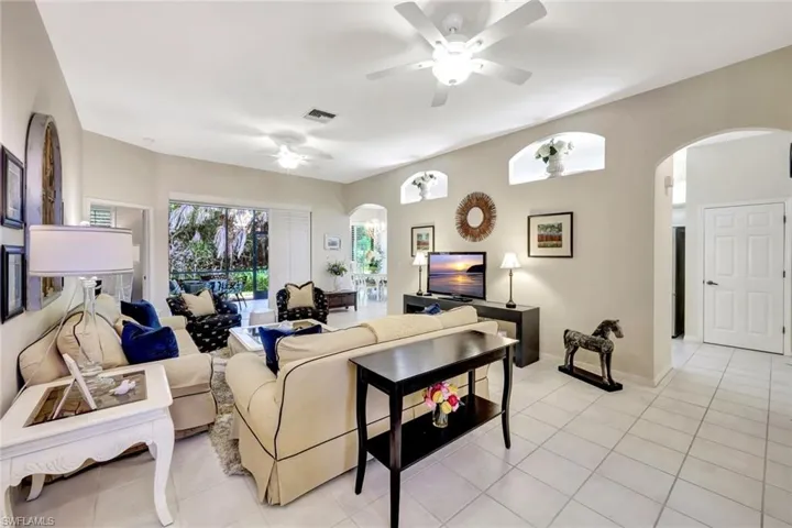 Living room with visible vents, arched walkways, light tile patterned floors, and a ceiling fan