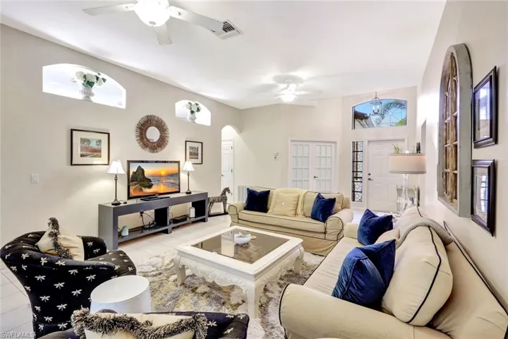 Tiled living area featuring visible vents, arched walkways, and a ceiling fan