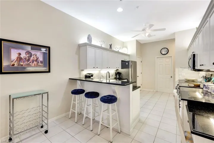 Kitchen featuring a ceiling fan, decorative backsplash, a kitchen breakfast bar, and stainless steel appliances