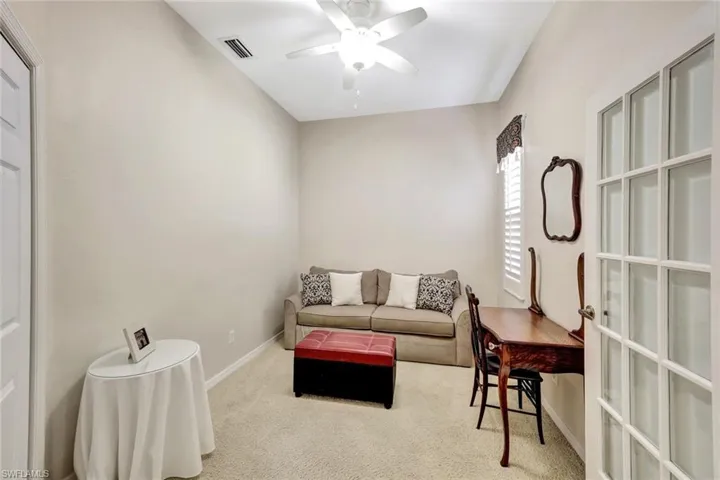 Living area featuring baseboards, visible vents, ceiling fan, and carpet