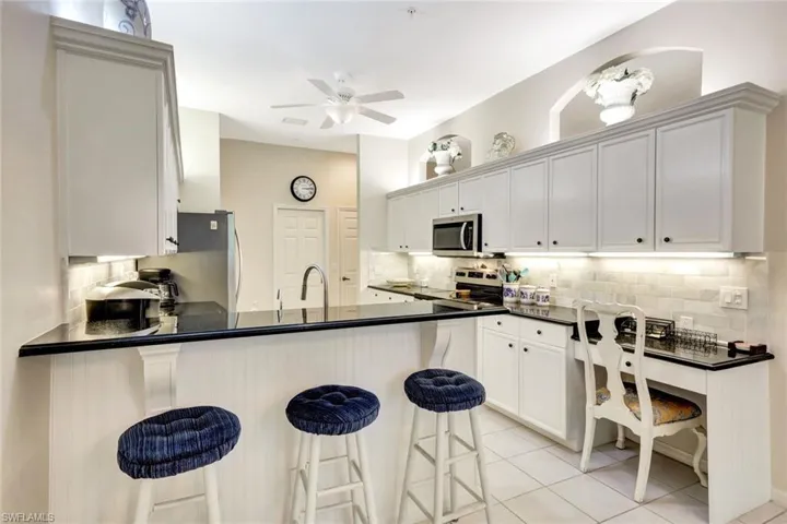 Kitchen featuring a ceiling fan, tasteful backsplash, appliances with stainless steel finishes, a peninsula, and dark countertops