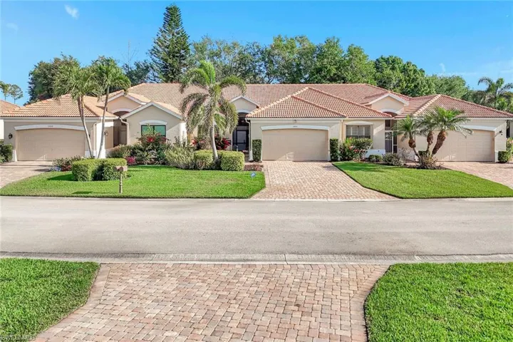 Mediterranean / spanish home featuring a front lawn, a tile roof, stucco siding, and an attached garage