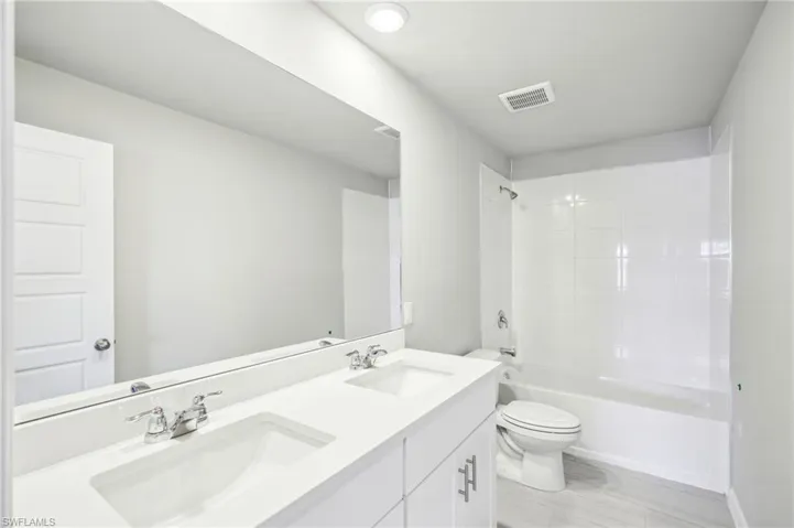 Full bathroom featuring tiled shower / bath combo, vanity, and toilet