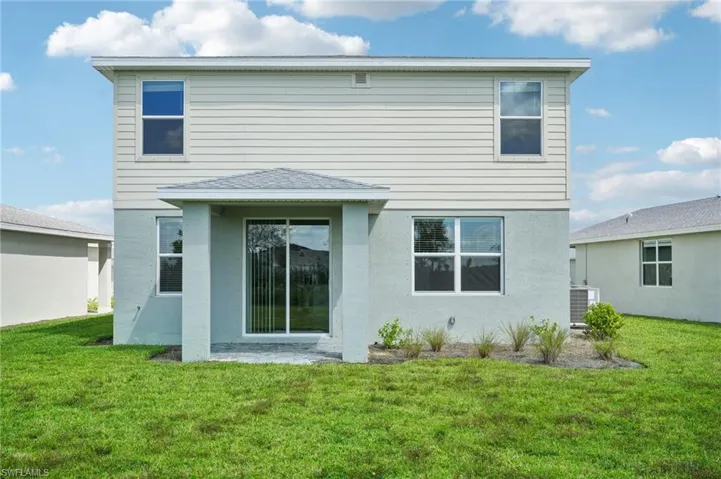 Back of house with a lawn and central air condition unit