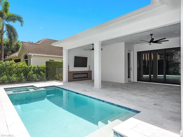 View of swimming pool featuring a pool with connected hot tub, fence, a ceiling fan, and a patio