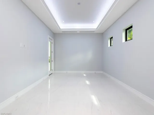 Spare room featuring a tray ceiling and baseboards
