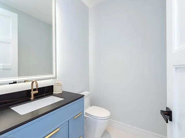 Half bath featuring baseboards, vanity, and toilet