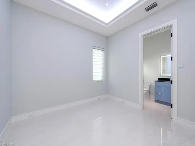 Unfurnished bedroom featuring marble finish floor, visible vents, baseboards, and ensuite bathroom