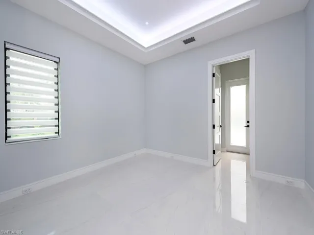 Empty room featuring marble finish floor, a raised ceiling, visible vents, and baseboards