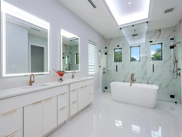 Full bath featuring a marble finish shower, a soaking tub, a sink, and visible vents