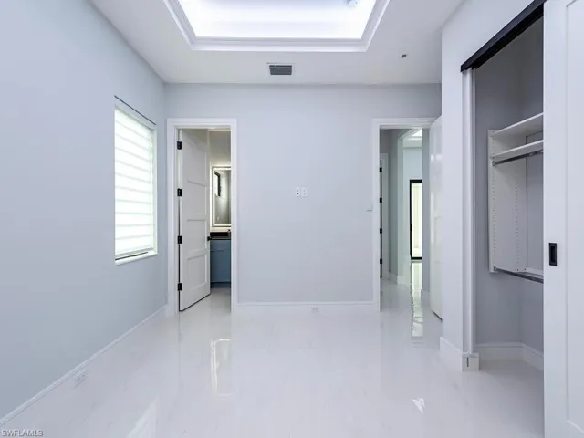 Hall featuring marble finish floor, visible vents, baseboards, and a tray ceiling