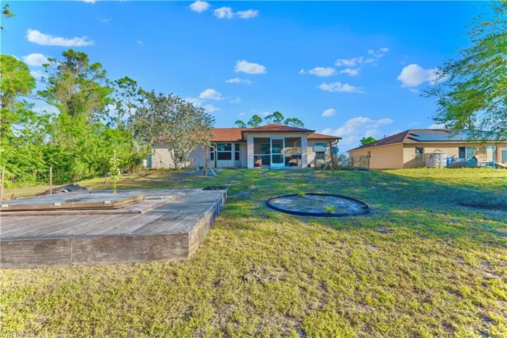 Back of property featuring stucco siding, a lawn, and a sunroom