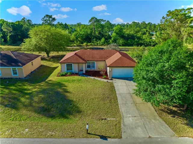 View of front of home with a front lawn, a garage, driveway, and stucco siding