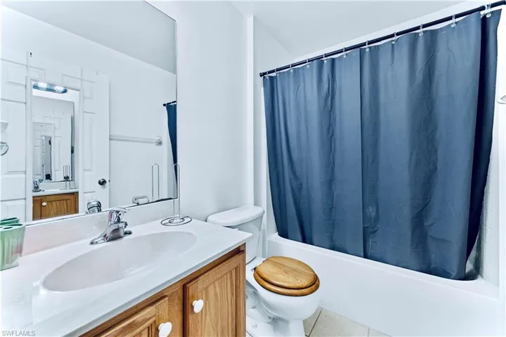 Bathroom with toilet, vanity, and shower / bath combination with curtain