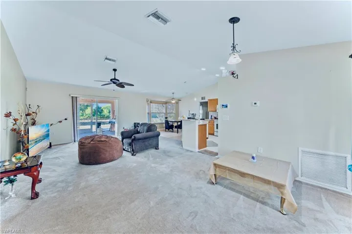 Living room with visible vents, light colored carpet, and vaulted ceiling