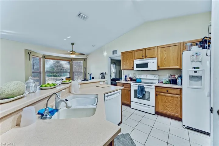 Kitchen with visible vents, a sink, white appliances, light countertops, and light tile patterned floors
