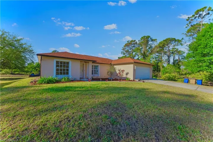 Ranch-style house featuring concrete driveway, an attached garage, a front yard, and stucco siding