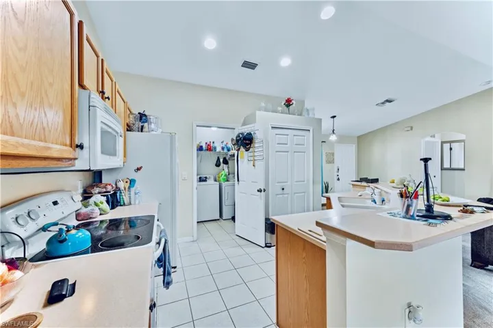Kitchen featuring visible vents, independent washer and dryer, white appliances, light countertops, and light tile patterned floors