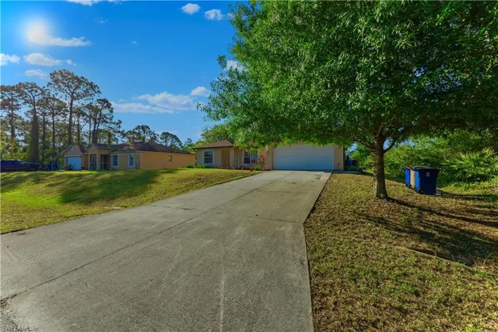 Ranch-style home with stucco siding, a front yard, an attached garage, and driveway