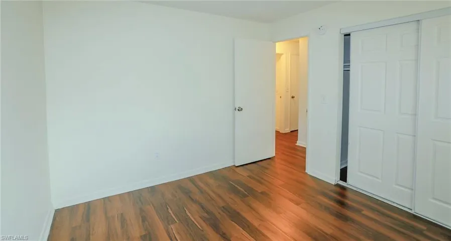 Wood-finish flooring, white walls, and a white sliding door closet
