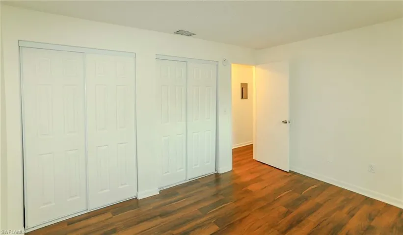 Wood-finish flooring, white walls, and built-in sliding closet doors