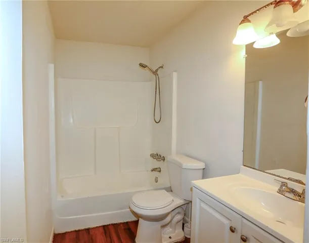 Full bathroom featuring a white vanity with integrated sink, a white toilet, and a combined shower-tub unit