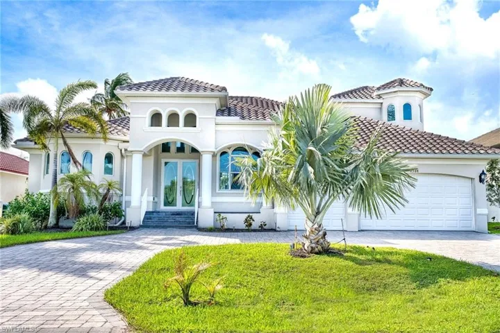 Stucco exterior with a tile roof, arched entryway, double glass entry doors, arched windows, and a paved driveway