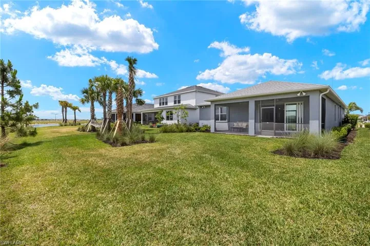 Back of property with a sunroom, a yard, a water view, and stucco siding