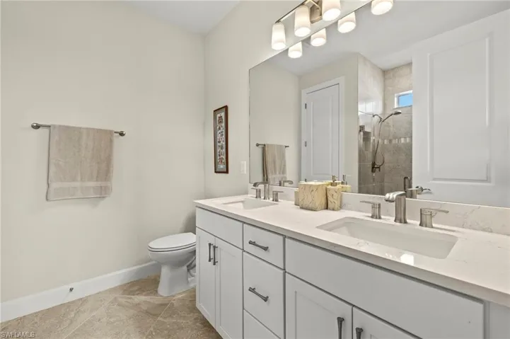 Bathroom with toilet, baseboards, a stall shower, and a sink