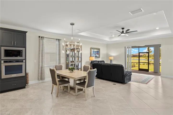 Dining room featuring ceiling fan with notable chandelier, visible vents, crown molding, a raised ceiling, and baseboards
