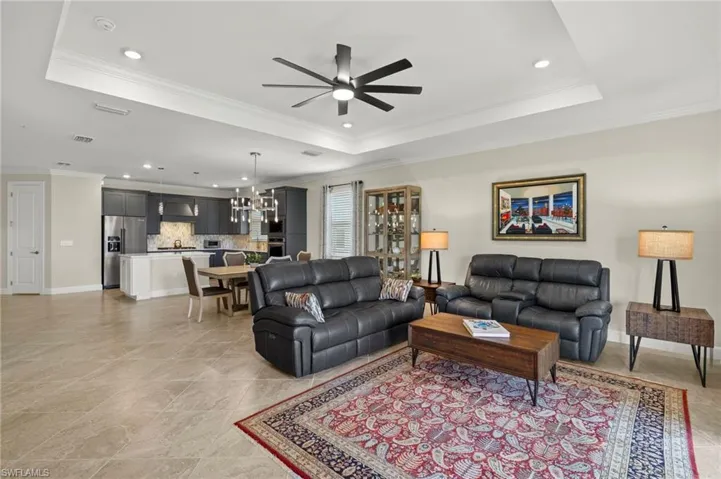 Living area featuring crown molding, a ceiling fan, a raised ceiling, and recessed lighting