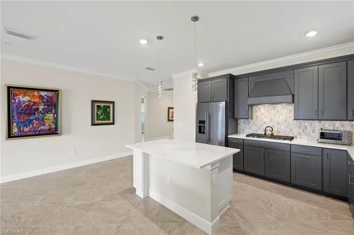 Kitchen with stainless steel appliances, crown molding, visible vents, backsplash, and custom exhaust hood