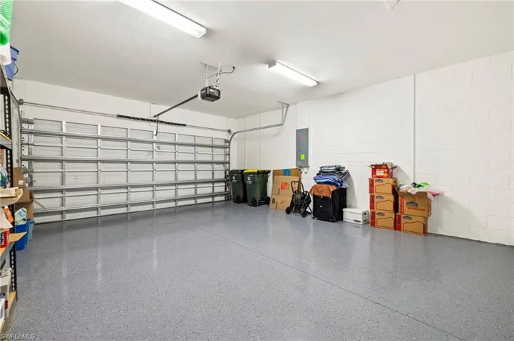 Garage featuring electric panel, concrete block wall, and a garage door opener