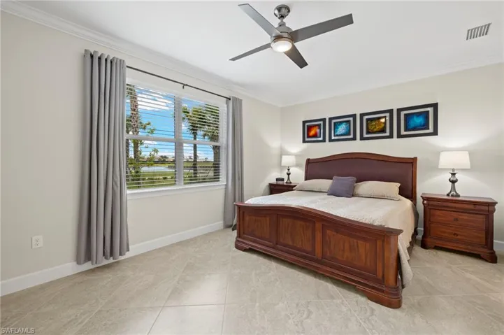 Bedroom with a ceiling fan, baseboards, light tile patterned floors, ornamental molding, and visible vents