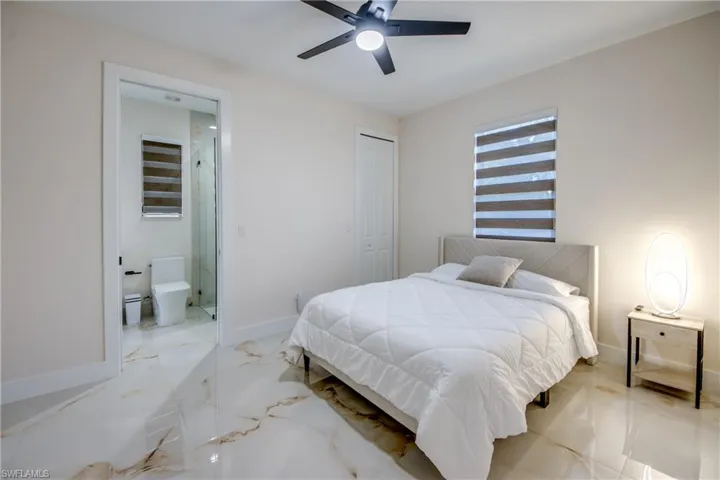 Spacious room featuring large format tile flooring, a modern ceiling fan, and a window with striped blinds