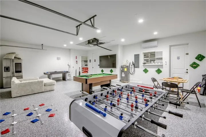 Spacious recreation room featuring a durable epoxy floor finish, recessed lighting, and white walls