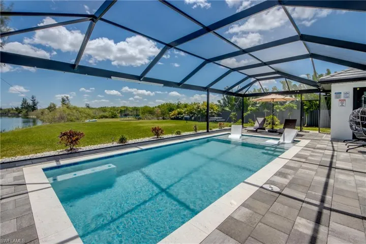 Screened-in outdoor pool featuring a sun shelf, paver patio, and water frontage