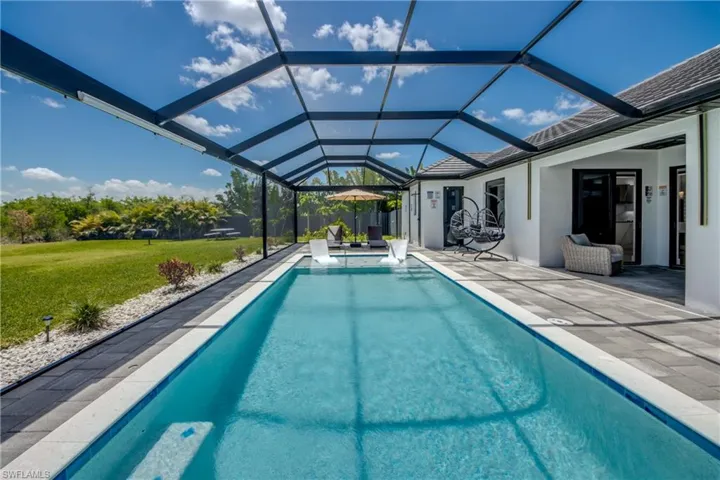 Expansive screened-in swimming pool featuring a rectangular design with a perimeter of light-colored coping
