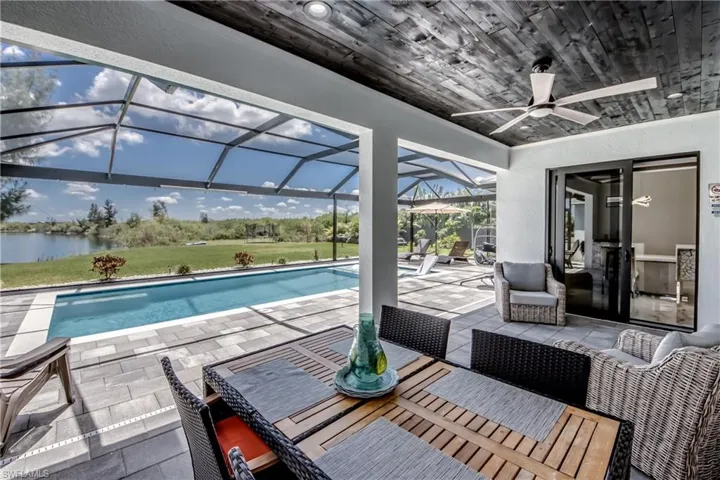Screened outdoor living area featuring a rectangular pool, paver patio, and lakefront setting