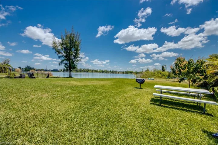 Expansive waterfront lawn featuring mature trees and a tranquil water body