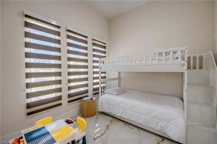 Spacious room featuring three windows with horizontal blinds and large-format porcelain tile flooring