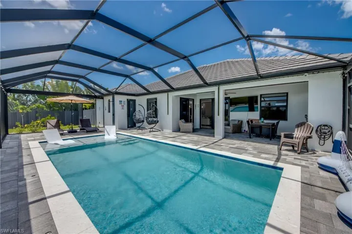 Screened-in outdoor living space featuring a rectangular pool, light-colored coping, paver patio, and a covered lanai