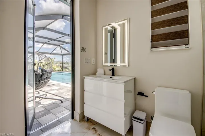Modern bathroom featuring a white vanity with integrated sink, black faucet, and an illuminated mirror