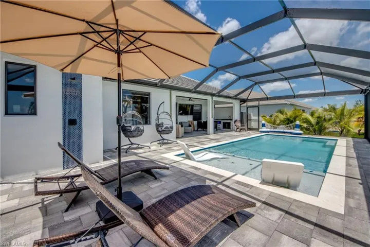 Screened outdoor living area featuring a rectangular pool with an integrated spa, paver decking, and a covered lanai