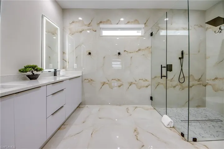 Expansive bathroom featuring a double vanity with quartz countertops, integrated sinks, and illuminated mirrors