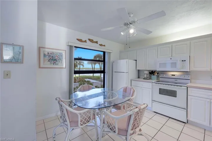 Kitchen featuring light tile patterned flooring, white appliances, light countertops, and ceiling fan