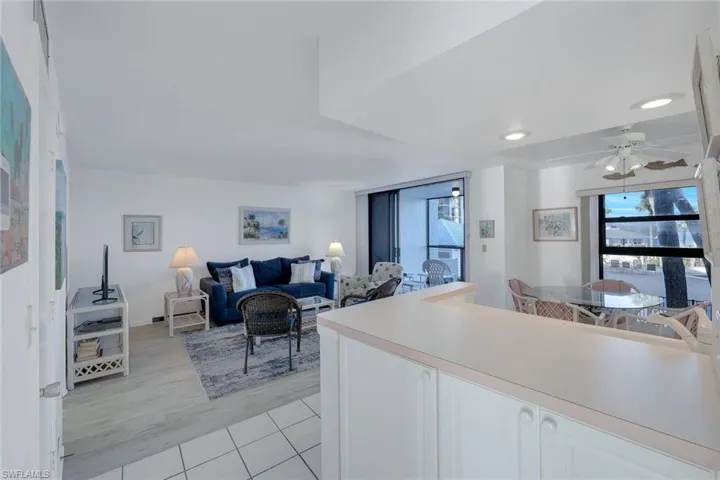 Kitchen featuring white cabinets, light countertops, a ceiling fan, light wood-type flooring, and open floor plan